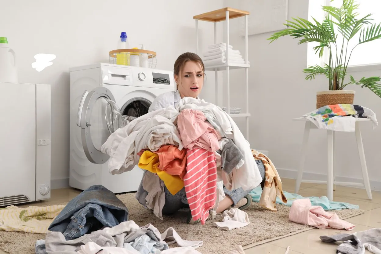 Donna stressata sommersa dal bucato da lavare